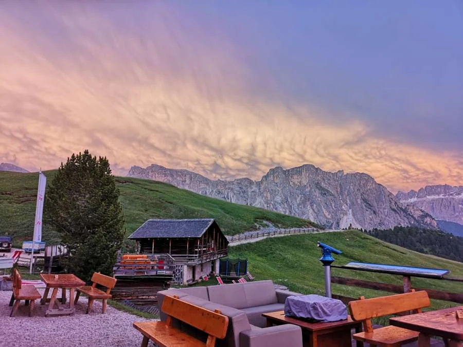 Rosa Abendwolken über der Geislergruppe, davor die Terrasse der Hütte