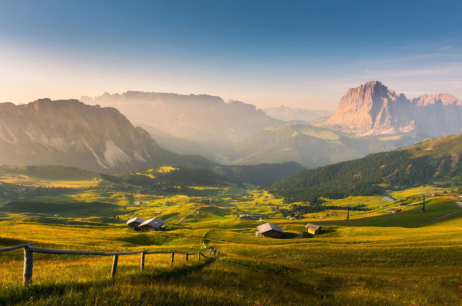 Gelbgrüne Almwiesen der Seceda im Sonnenlicht, dahinter der Langkofel